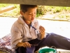 Young boy finds some shade under a table to eat his snack